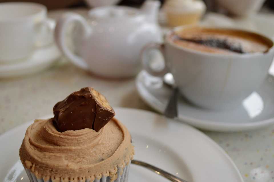 A Snickers cupcake with a mocha in the background